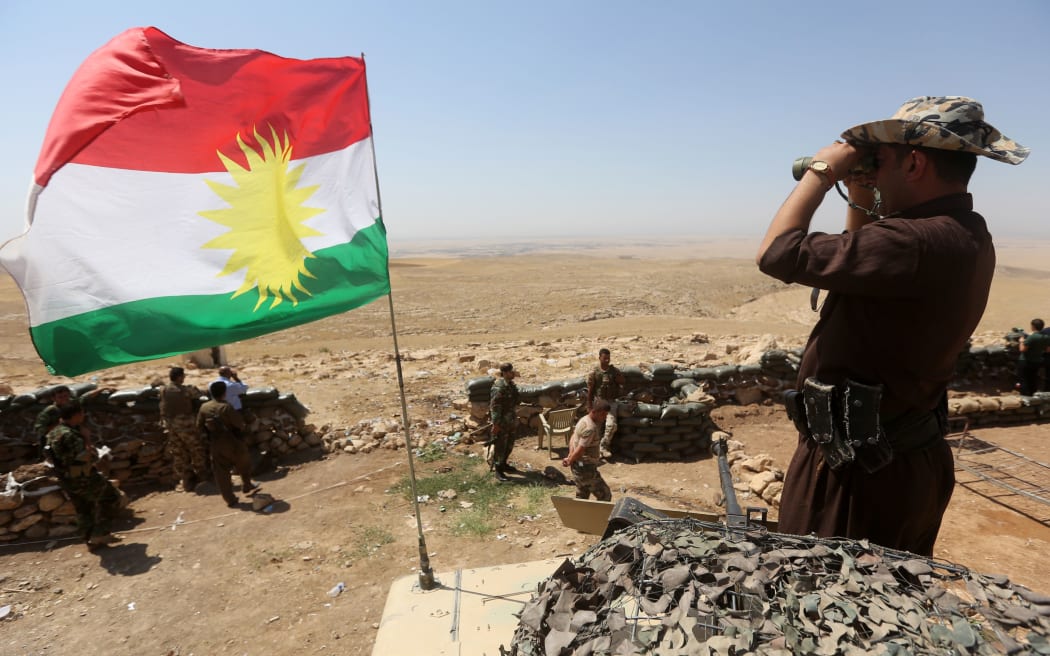 A flag of the autonomous Kurdistan region flies as Peshmerga fighters take position in Bashiqa, a town 13 kms north-east of Mosul.
