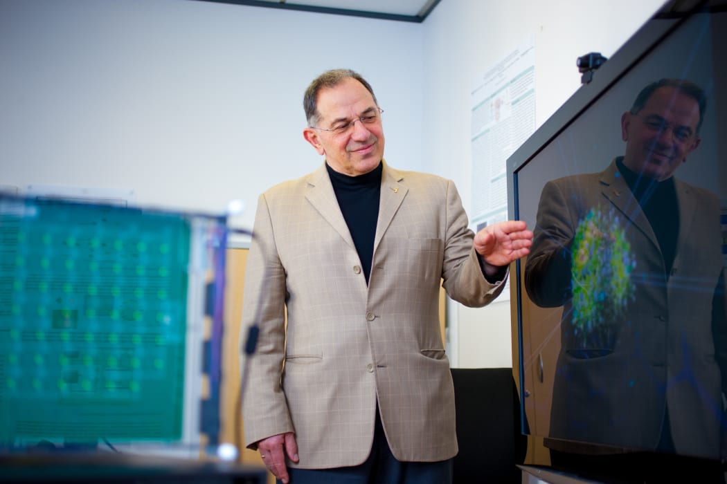 Nikola Kasbov standing in front of a monitor showing a graphical representation of a neural network