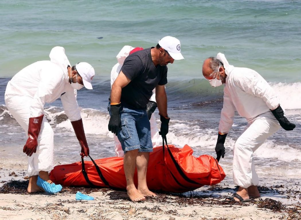 Members of the Libyan Red Crescent move the body of a migrant washed ashore on a beach after a boat carrying hundreds of migrants sank off the coast of Zuwarah, Libya.