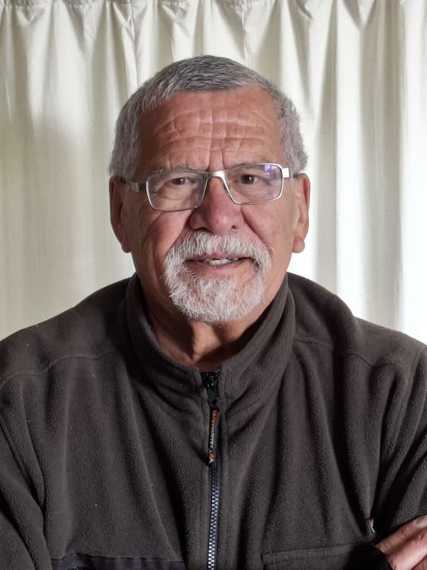 Harry Walker looks at the camera in spectacles and a brown sweater.