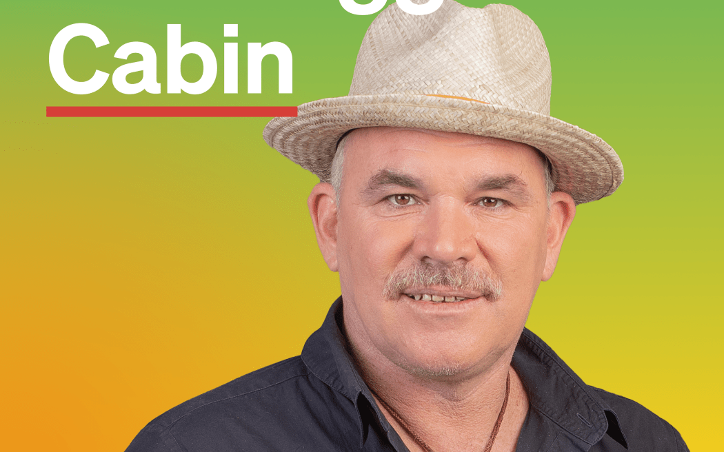 A photo of Mark Williams in front of a gradient that goes from green to yellow and orange. Text 'The Logg Cabin' sits in the top left. The RNZ tohu sits in the bottom left.