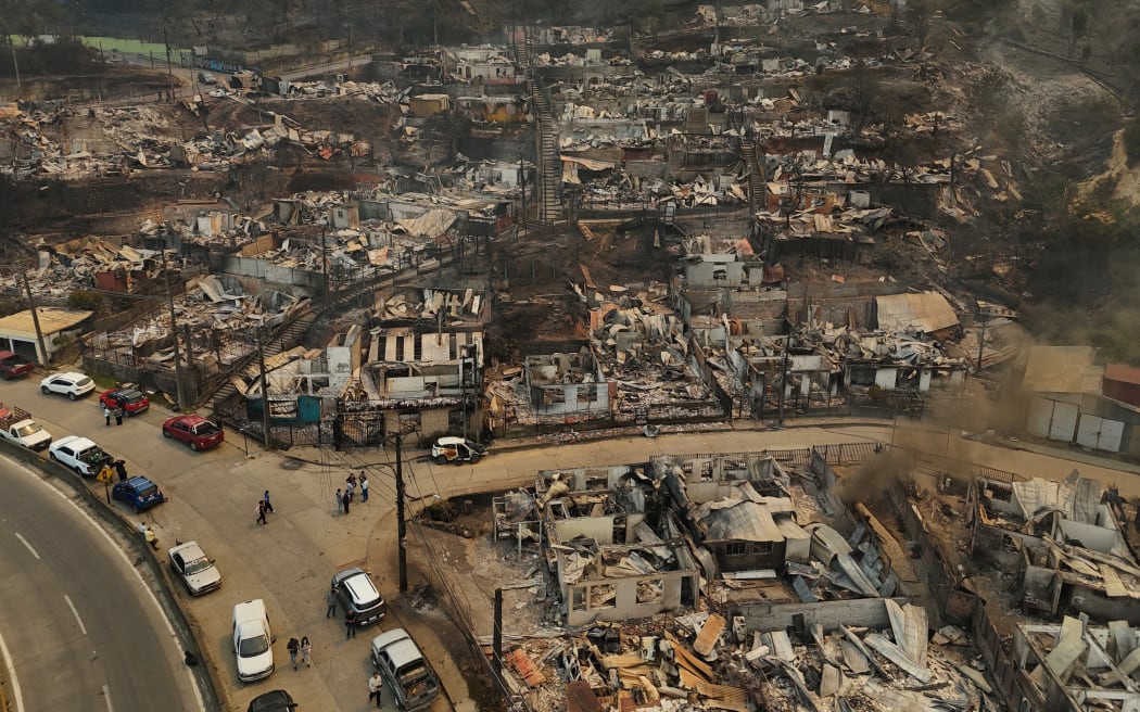 Aerial view of the charred remains of destroyed homes after a wildfire in Concepcion, Chile, on January 18, 2026. Chilean President Gabriel Boric declared a state of emergency on January 18 for two southern regions where raging wildfires have forced about 20,000 people to evacuate their homes. (Photo by Raul BRAVO / AFP)