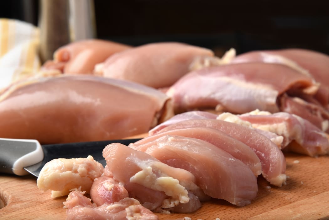 A closeup of fresh chicken meat on a wooden board.