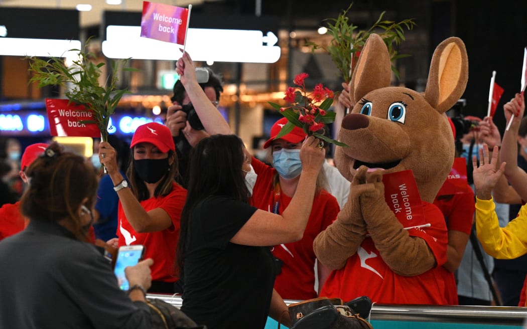 Staff offer flowers to passengers upon their arrival at Sydney International Airport on 21 February, 2022, as Australia reopened its borders for fully vaccinated visa holders, tourists, and business travellers.