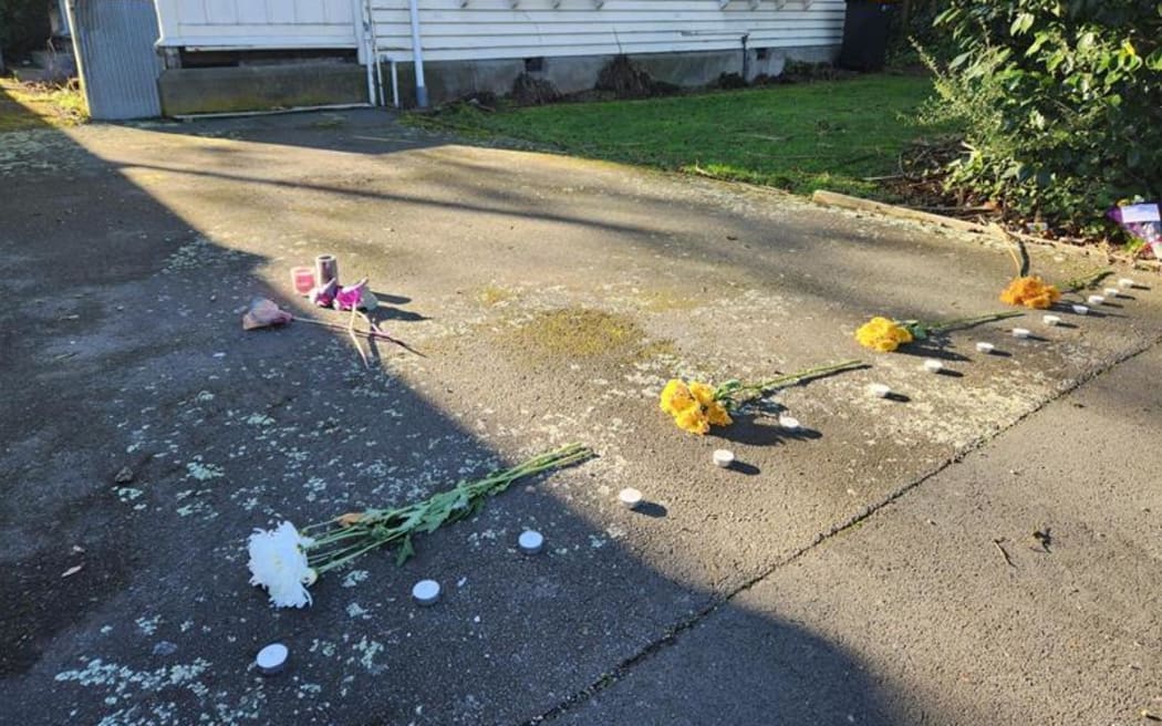 Flowers and candles laid on the driveway of a property on Gracefield Avenue, where police found a body believed to be that of Elisabeth Nicholls on Sunday.