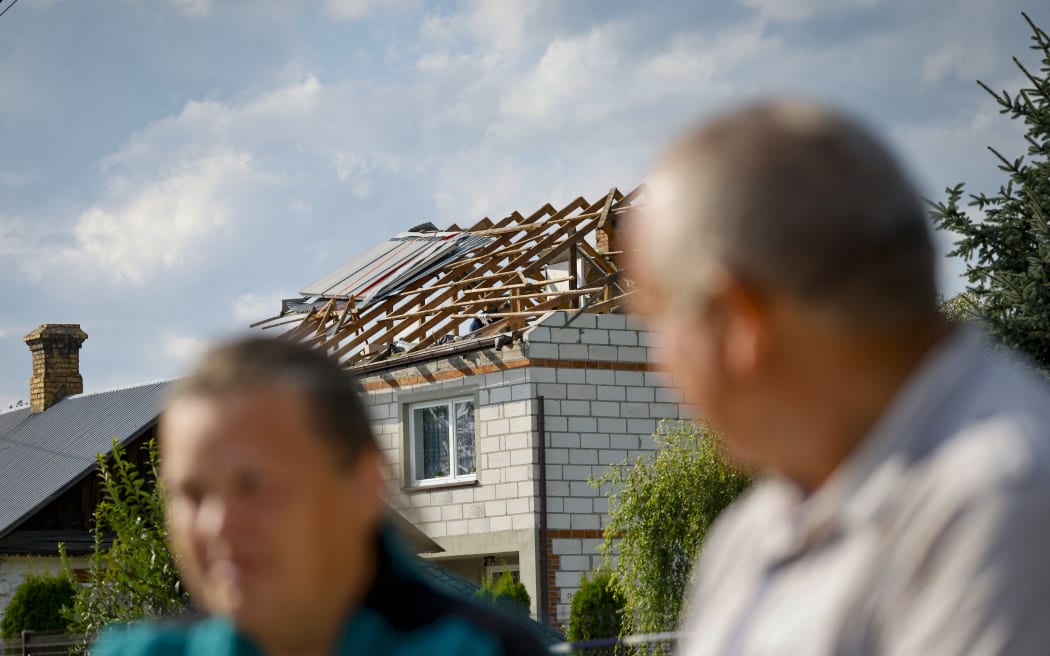 Alicja (L) sits next to her husband Tomasz Wesolowscy as police and army inspect damage to their house destroyed by debris from a shot down Russian drone in the village of Wyryki-Wola, eastern Poland, on September 10, 2025. NATO air defences helped counter drones that entered Polish airspace overnight and alliance chief Mark Rutte is in contact with Warsaw, a NATO spokeswoman said Wednesday. Polish Prime Minister Donald Tusk said Wednesday that a violation of Polish airspace by several Russian drones overnight was a major provocation aimed at the EU and NATO member. (Photo by Wojtek RADWANSKI / AFP)