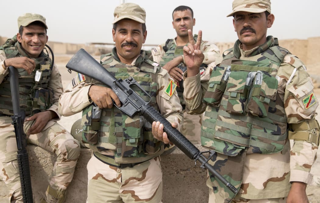 Four Iraqi soliders in full kit and armed line up for photos.