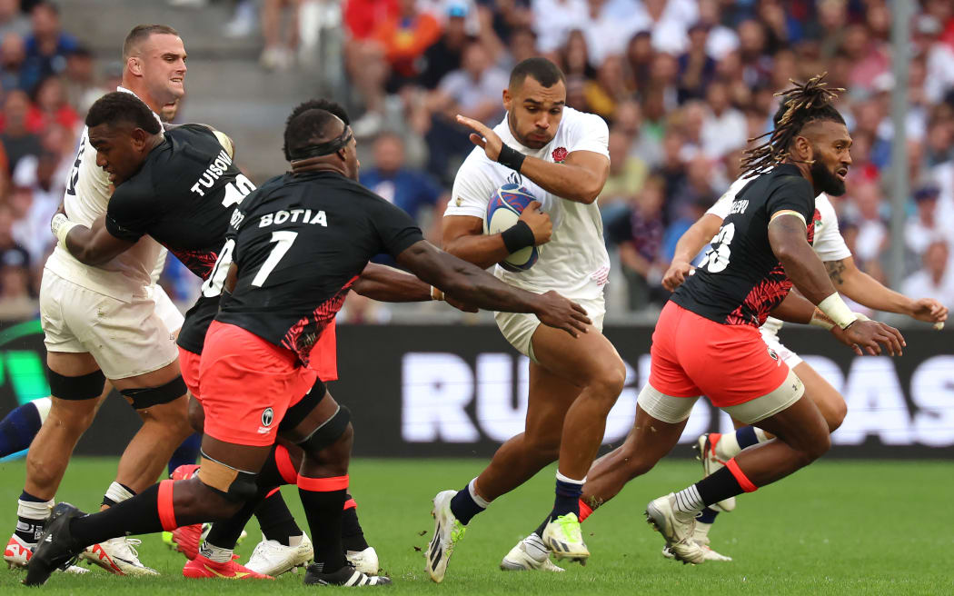 England's outside centre Joe Marchant (C) tries to avoid the tackle of Fiji's openside flanker Levani Botia (3rdL) during the France 2023 Rugby World Cup quarter-final match between England and Fiji at the Velodrome stadium in Marseille, south-eastern France, on October 15, 2023.