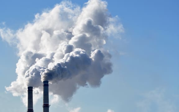Industrial smoke from a chimney against blue sky