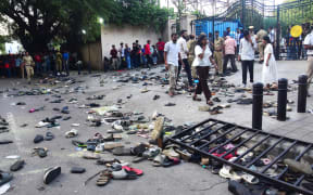 Fans stand next to abandonned shoes and a fallen barrier following a stampede during celebrations, a day after Royal Challengers Bengaluru's victory at the Indian Premier League (IPL) Twenty20 final cricket match, outside the M. Chinnaswamy Stadium in Bengaluru on June 4, 2025. At least 11 people were killed in a stampede on June 4, as a tightly packed crowd celebrated the victory of their home cricket team in the Indian city of Bengaluru, the state's chief minister said. (Photo by AFP)