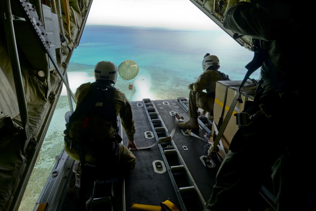 Australian Army Cpl. Teome Matamua and Sgt. Phillip McIllvaney, 176th Air Dispatch Squadron loadmasters, deliver the first low-cost, low-altitude bundle of Operation Christmas Drop 2015 to the island of Mogmog, Dec. 8, 2015.