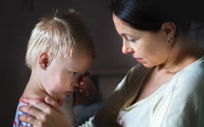 A photo of a mother comforting a small boy who looks distressed