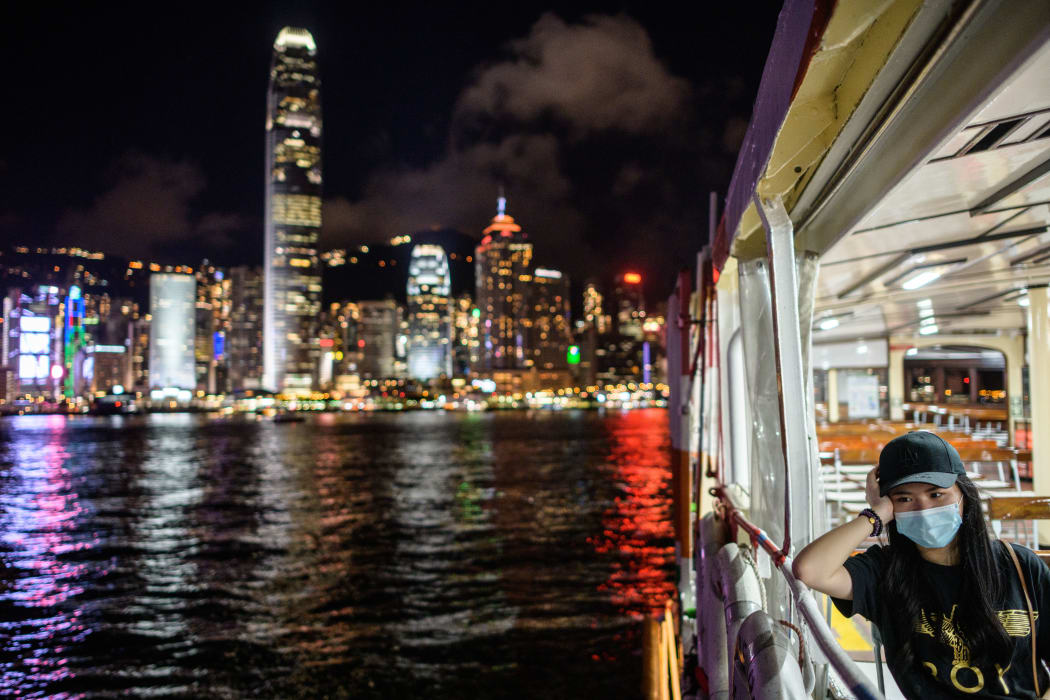 A woman on a passenger ferry in Victoria Harbour travelling away from Kowloon to Hong Kong Island