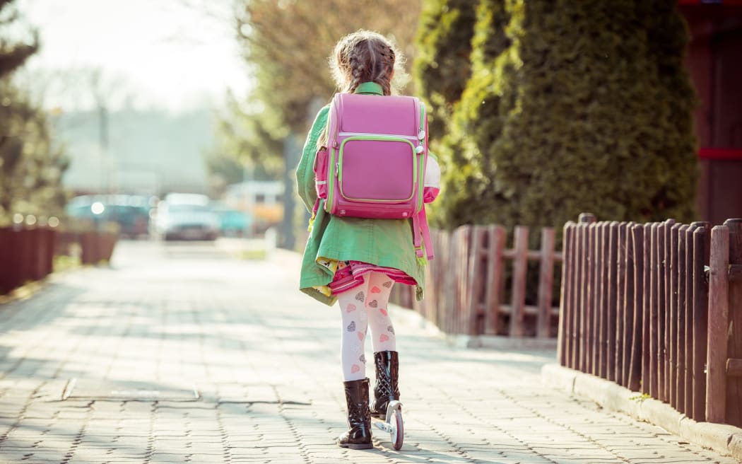 girl goes to school on a scooter. back view
