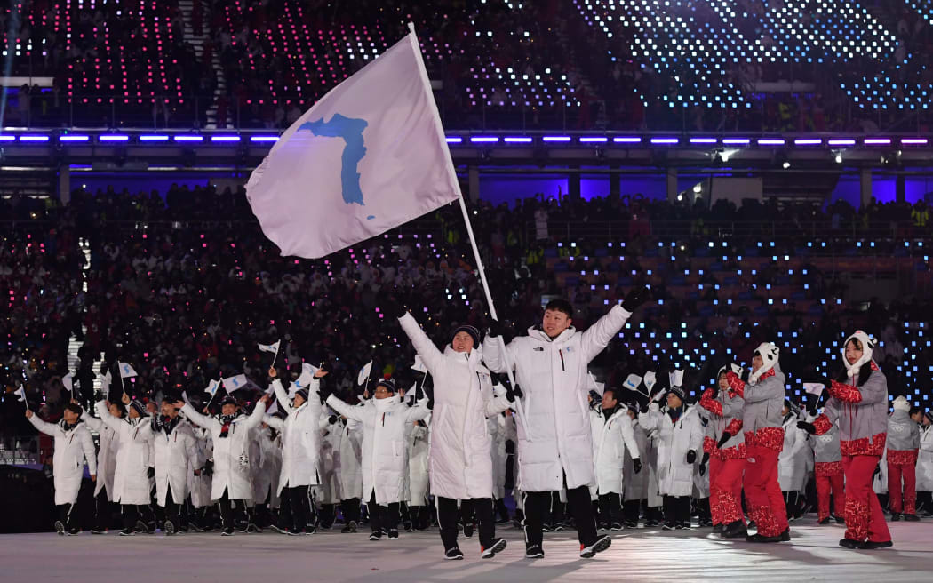 North and South Korean  flagbearers wave to the crowd.