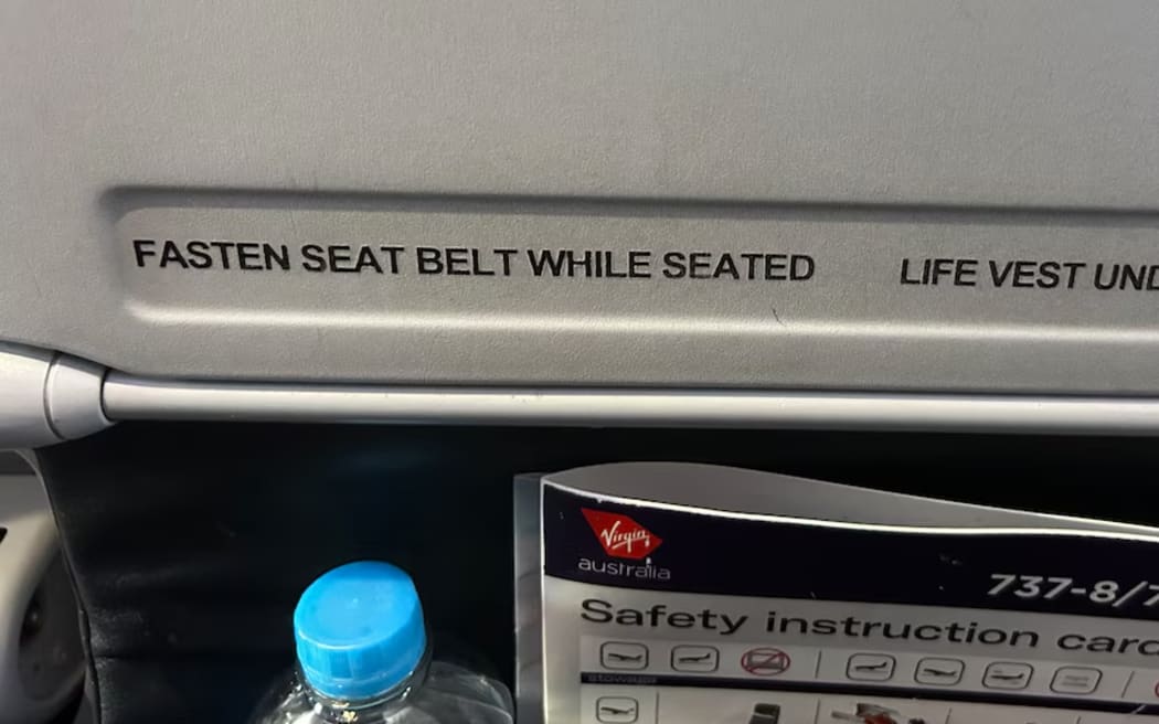 Sign on back of airplane seat reading 'Fasten seat belt while seated'