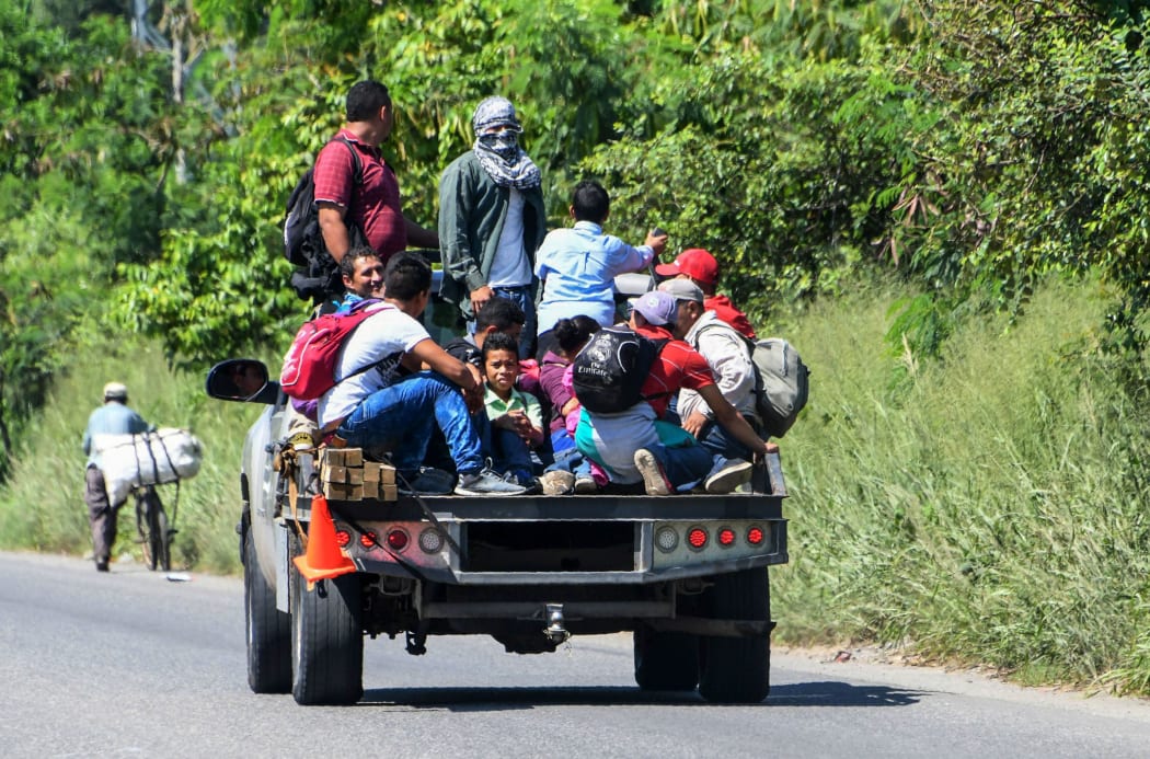 Hondurans get on vans and trucks during the exodus towards the US from San Pedro Sula