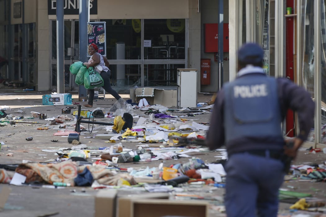 A looter runs from a member of the South African Police Services (SAPS) inside the Lotsoho Mall in Katlehong  township, East of Johannesburg, on July 12, 2021.