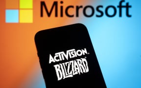 The Activision Blizzard logo is seen with a Microsoft logo in the background in this photo illustration on 13 July, 2023 in Warsaw, Poland.