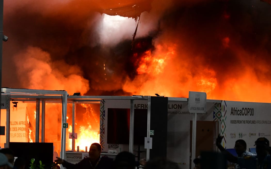 A fire burns in a pavilion during the COP30 UN Climate Change Conference in Belem, Para state, Brazil, on November 20, 2025. A fire erupted at a pavilion inside the venue of the UN's climate talks in Brazil on Thursday, prompting panicked delegates to run for the exits, AFP journalists said. Emergency crews rushed to try to put out the blaze as smoke engulfed the corridor. (Photo by JACQUELINE LISBOA / AFP)