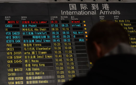 A man stands beside the arrival board showing the flight MH370 at Beijing Airport.