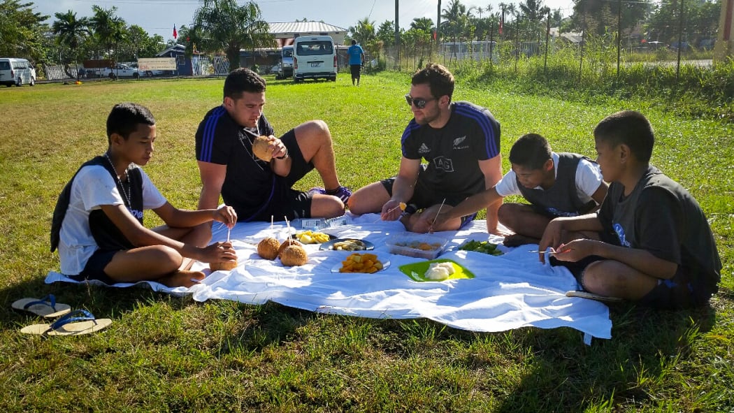 All Blacks Codie Taylor and Tom Taylor share some fruit with local children.