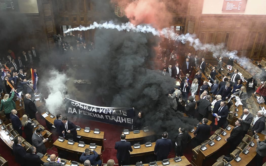 Smoke fills Serbia's parliament on 4 March as lawmakers unroll a banner that reads: "Serbia rises up to bring down the regime."