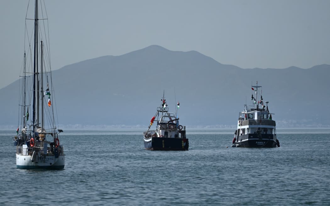 A ship (R), known as the "Family" and is part of the Global Sumud Flotilla, is anchored off the coast of the village of Sidi Bou Said on September 9, 2025. Organisers of a Gaza-bound flotilla carrying aid and pro-Palestinian activists said late on September 8, that one of their boats, known as the "Family",  was hit by a suspected UAV off the coast of Tunisia, but authorities there said "no drones" had been detected. (Photo by FETHI BELAID / AFP)
