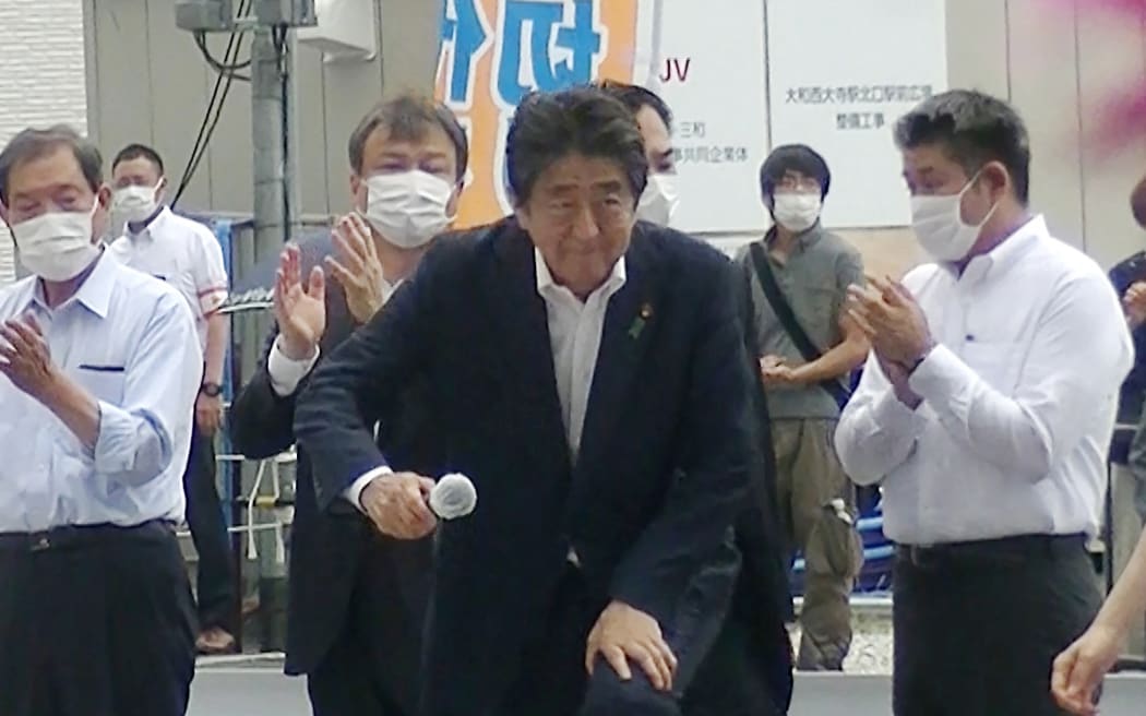 Shinzo Abe (C) attending an election campaign before giving a speech at Kintetsu Yamato-Saidaiji station square in Nara, while a man (2nd R-behind) suspected of shooting Abe shortly after stands in the background.