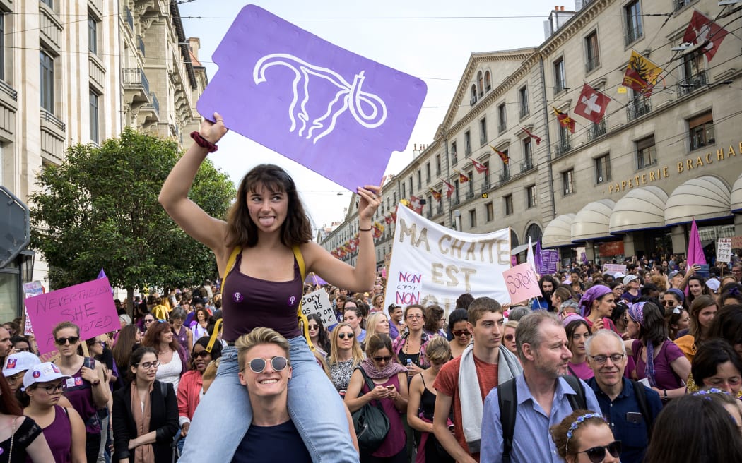 A woman holds up a placard depicting a uterus as she takes part in a nation-wide women's strike for wage parity, on June 14, 2019 in Geneva.