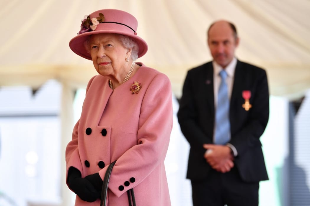 Britain's Queen Elizabeth II speaks with staff including Professor Tim Atkins (R), who was honoured for his work on the 2018 Novichok incident and has been involved in the fight against Covid-19.