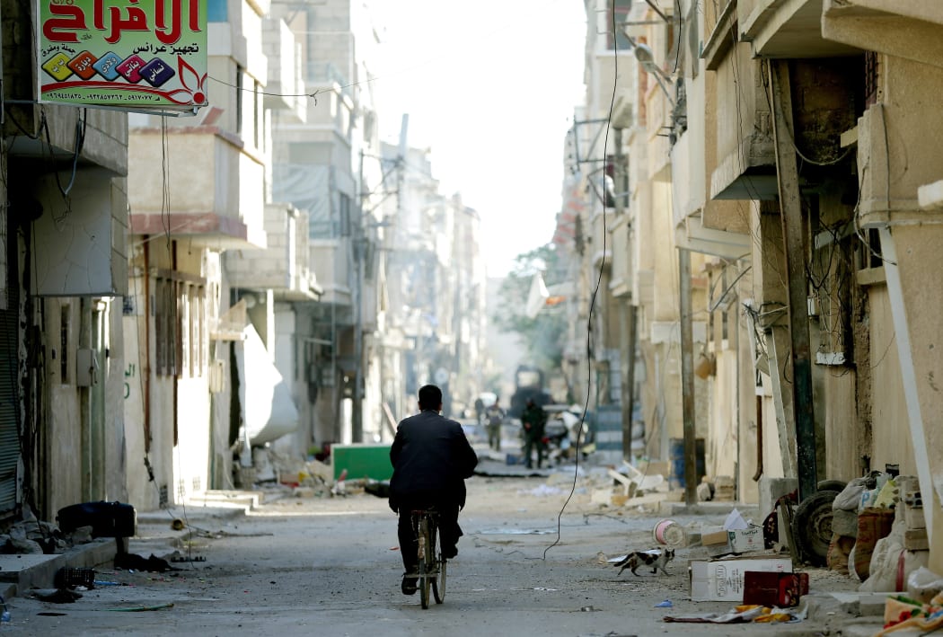 A Syrian man rides his bicycle on a street on March 31, 2016 in the modern town, adjacent to the ancient Syrian city of Palmyra.