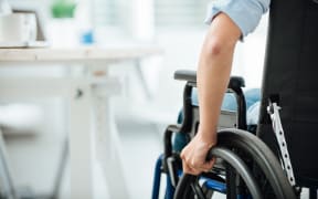 Woman in wheelchair next to an office desk, hand close up, unrecognizable person