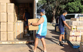 Moana Pasifika players Isi Tu'ungafasi and Don Lolo Penitau Finau loading up the containers of supplies for Tonga