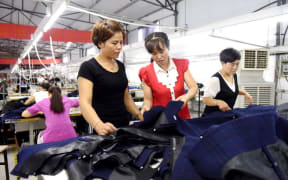 Bai Shuxiang (C) and Du Caizhi (L) from Qiandong Village of Nanhe County, north China's Hebei Province, examine products' quality at a local anti-poverty factory,