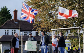 Protesters with St George Cross and union flags gather outside the Bell Hotel in Epping on August 29, 2025, after the appeals court overturned a decision temporarily blocking the use of the hotel to house asylum seekers. A UK appeals court on August 29 overturned a lower court decision temporarily blocking the use of a protest-hit hotel to house asylum-seekers, handing a badly-needed victory to the government. A three-judge panel ruled the High Court judge who previously imposed a September 12 deadline to remove migrants from the hotel in Epping, northeast of London had "made a number of errors". (Photo by CARLOS JASSO / AFP)