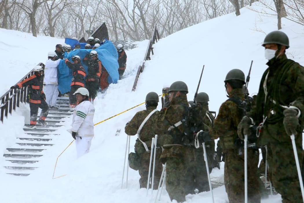 Firefighters carry a survivor they rescued from the site of the avalanche.