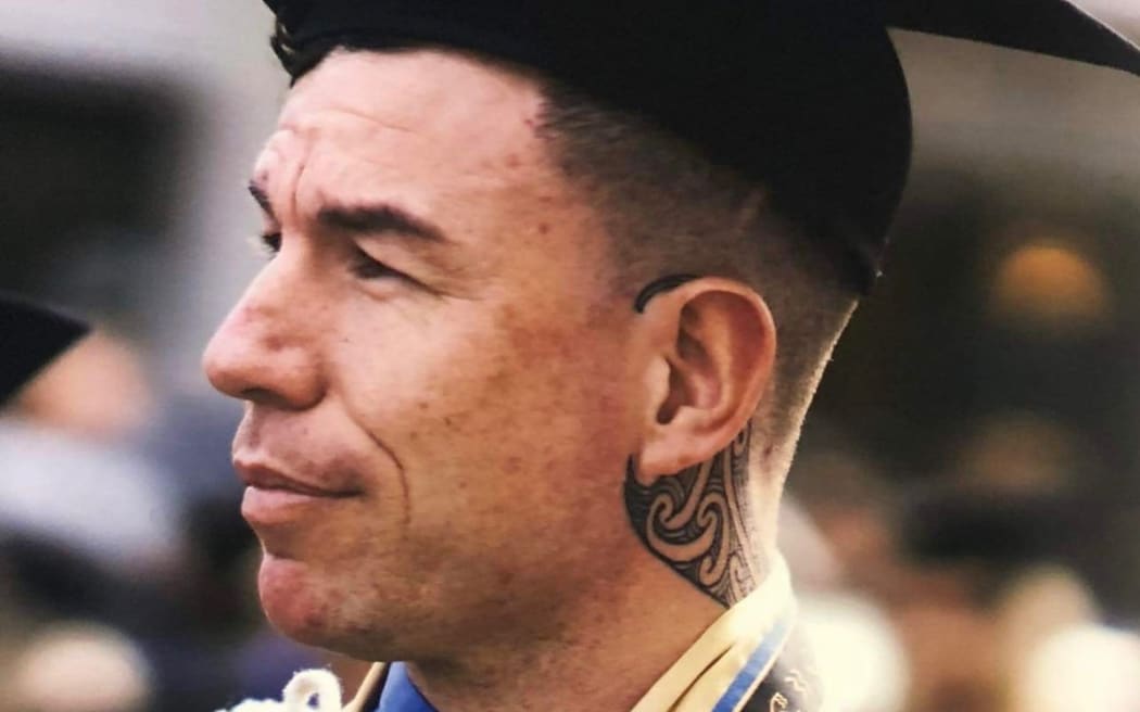 Levi Armstrong is dressed in graduation robes and the classic graduate hat. It's a close up of his face. He is looking towards the left side of the frame.