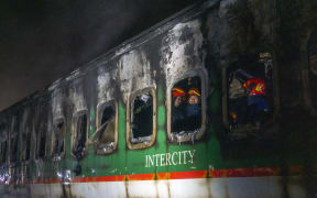 Firefighters search through a passenger train that was engulfed in flames ahead of the general election in Dhaka, Bangladesh, on 5 January.