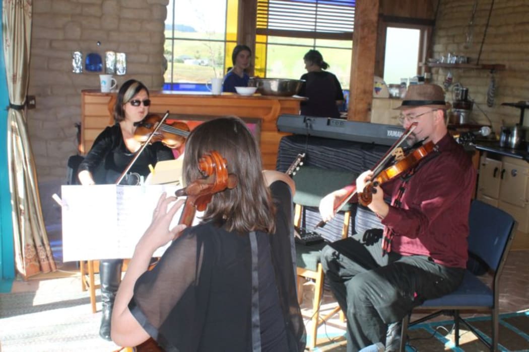 This is an image of The Auckland Trio playng at the Earth House. Elena Abramova;violin, Greg McGarity; viola and keyboard; and Sarah Spence, cello