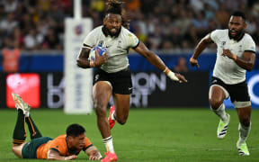 Fiji's outside centre and captain Waisea Nayacalevu, centre, runs with the ball after breaking through a tackle from Australia's centre Lalakai Foketi, left,  during the France 2023 Rugby World Cup Pool C match between Australia and Fiji at Stade Geoffroy-Guichard in Saint-Etienne, south-eastern France on September 17, 2023.