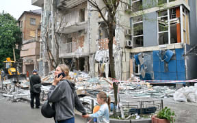 People walk past a multistory residential building  damaged following  a drone strike in Kyiv on May 25, 2025, amid Russian invasion in Ukraine. Russia launched a record number of drones against Ukraine and killed 12 people across the country, officials said on May 25, even as Kyiv and Moscow completed their biggest prisoner exchange since the start of the war. (Photo by Sergei SUPINSKY / AFP)