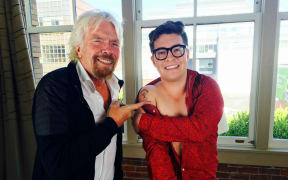 Jake Millar shows Richard Branson his tattoo. "The tattoo is a replica of a parachute my late father drew on my 10th birthday card. Underneath the parachute, it says 'Screw It, Let's Do It,' which is one of Richard's main quotes."