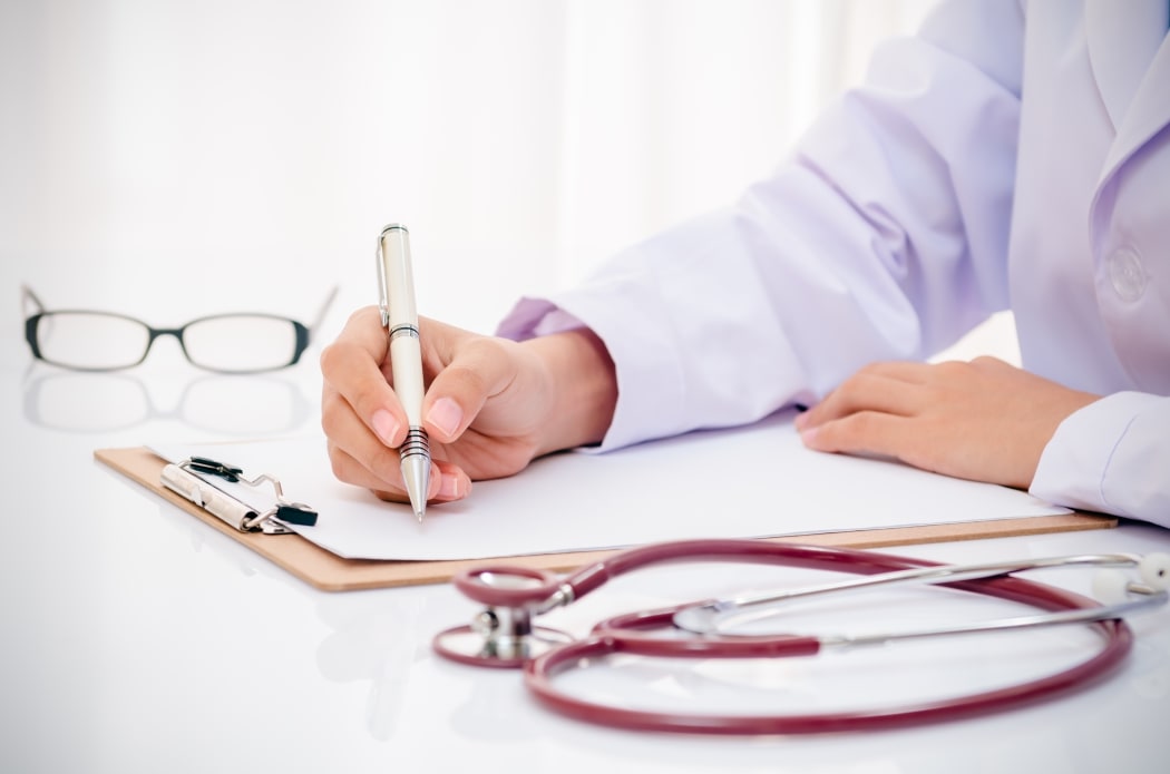 A doctor with a stethoscope writes up a medical record