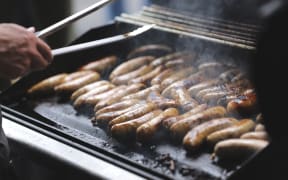 Sausages being cooked on a barbeque for National leader Christopher Luxon's visit to Morrinsville on the campaign trail.