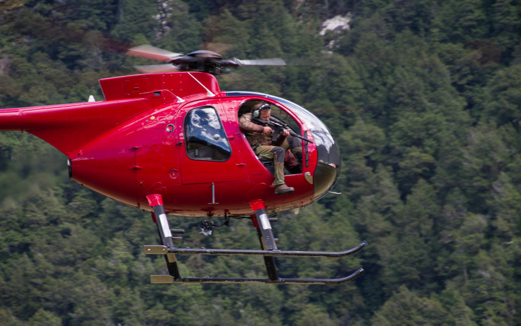 Man using shotgun outside of helicopter