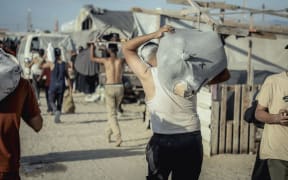 Dislocated Palestinians carry the humanitarian aid they have received from a United Nations distribution point in Rafah, southern Gaza Strip on May 27, 2025, following a chaotic incident in which Gazans stormed the aid center, leading to the withdrawal of the American company overseeing the operation after losing control of the situation. The scene underscores the desperation and urgency surrounding the humanitarian crisis as aid systems struggle to meet the overwhelming needs of the population. (Photo by Saeed Jaras / Middle East Images / Middle East Images via AFP)
