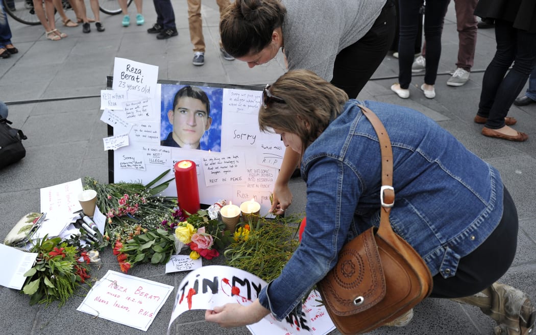People places flowers and cards next to the portriat of Iranian asylum seeker Reza Berati during a candlelight vigil in support of asylum seekers, in Melbourne on February 23, 2014.