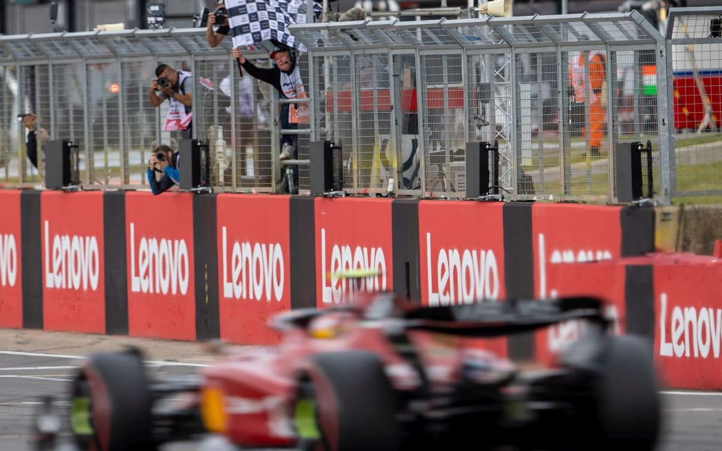 Scuderia Ferrari driver Carlos Sainz Jr takes the chequered flag at Silverstone in 2022.