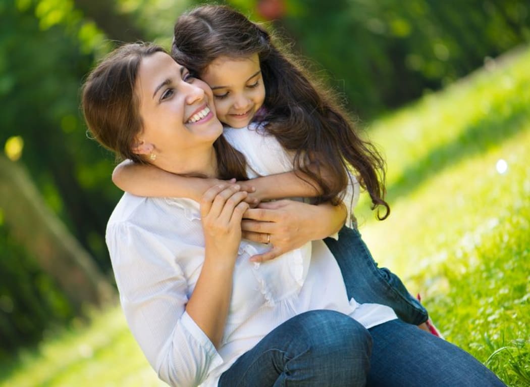 A photo of a happy young mother with her daughter at park